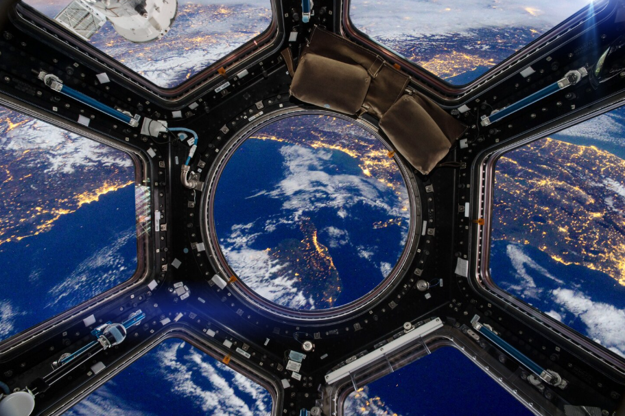 View of Earth’s city lights and atmosphere through a spacecraft window, illustrating space tourism.