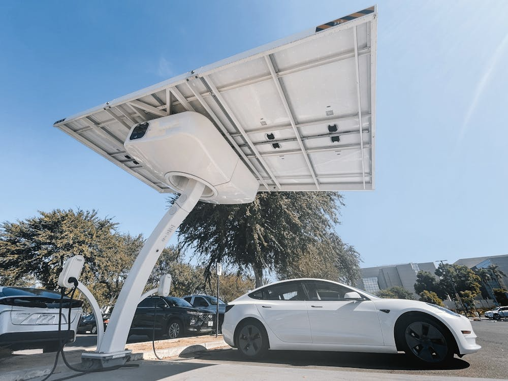 White electric car at a solar canopy fast charger, featuring the next-generation battery technology in action.