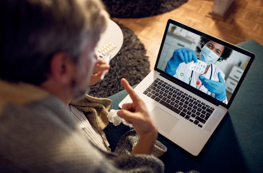 Older man on a video call with a masked doctor, illustrating telehealth and teletherapy care.