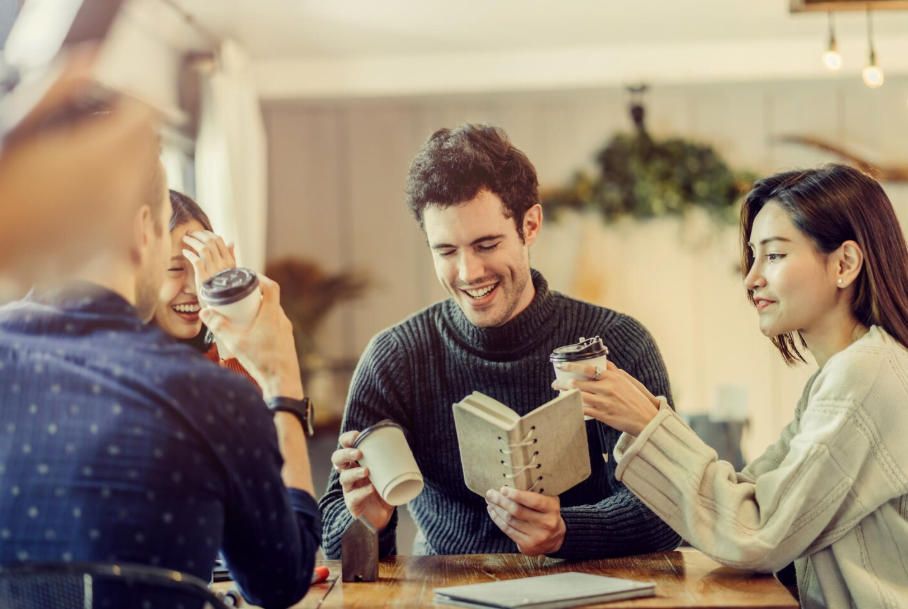 Group of adults laughing and chatting at a café book club, phones down, rebuilding connection.