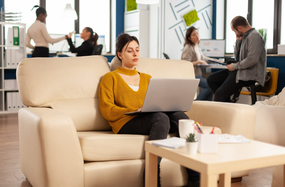 Professional using a laptop on a lounge chair in a modern office setting, illustrating the future of hybrid work.