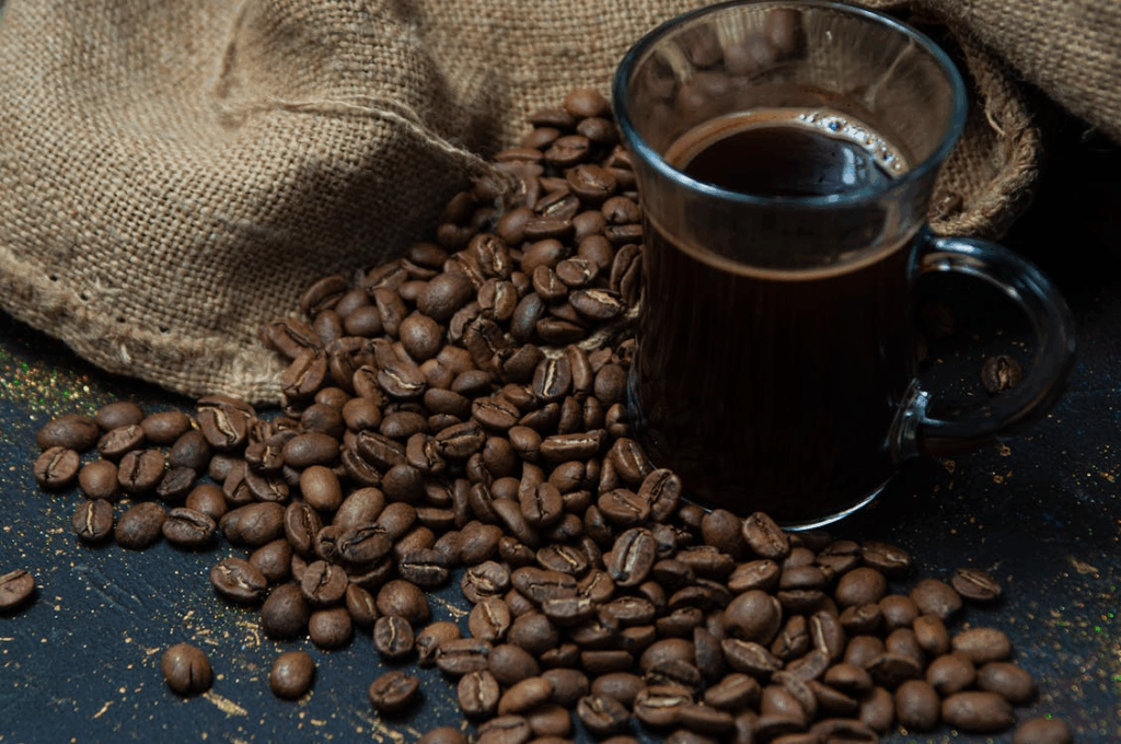Mug of black coffee beside a burlap sack of roasted beans, illustrating the global coffee shortage