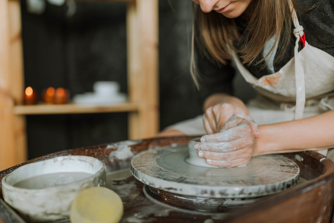 Close-up of an adult shaping clay on a pottery wheel, illustrating craft hobbies for adults.
