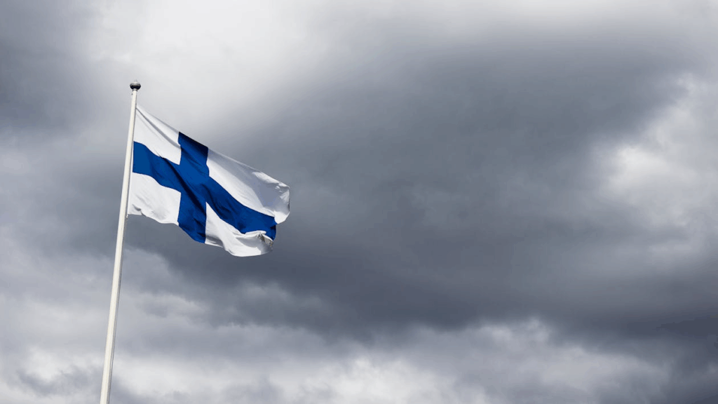 Finland’s national flag waving on a pole, symbolizing its top spot in the world happiness report.