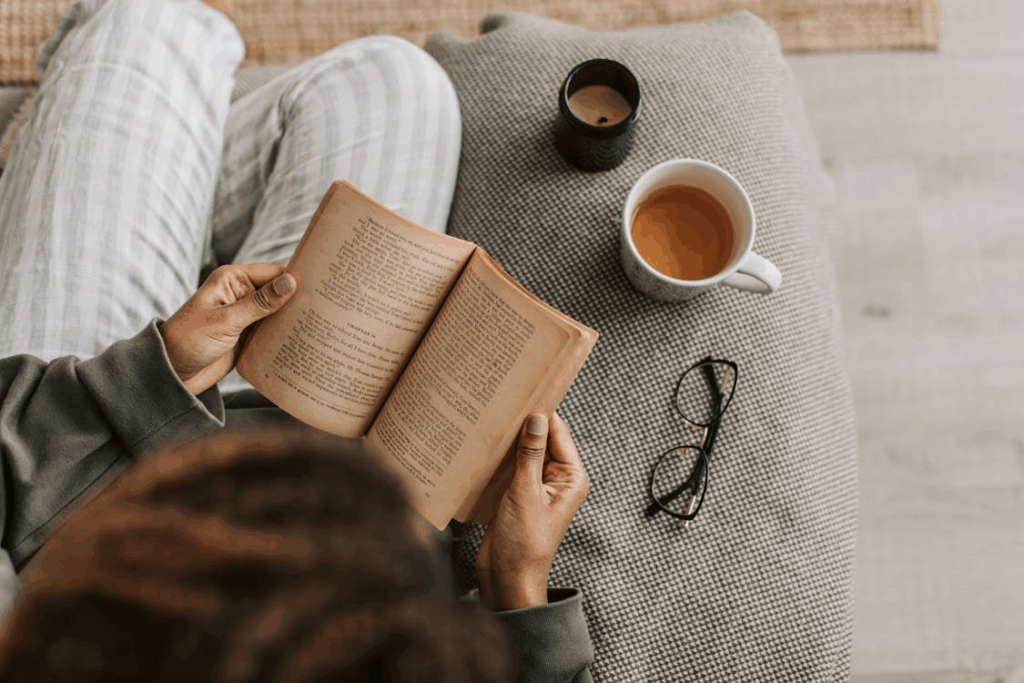 Person reading a paperback with tea—an evening routine that supports a daily reading habit.